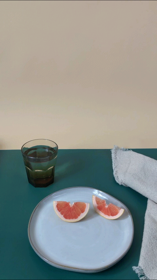the paring knife by prepared kitchenware being placed down on a plate with freshly cut grapefruit