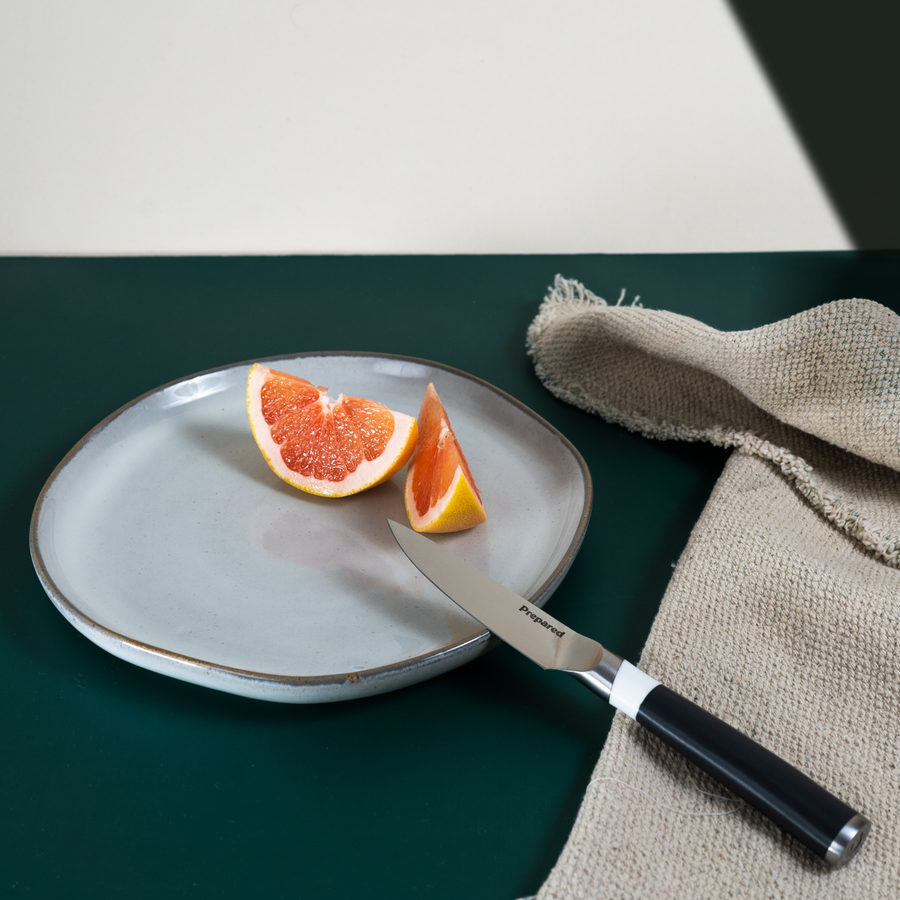  paring knife resting on a plate of fresh grapefruits